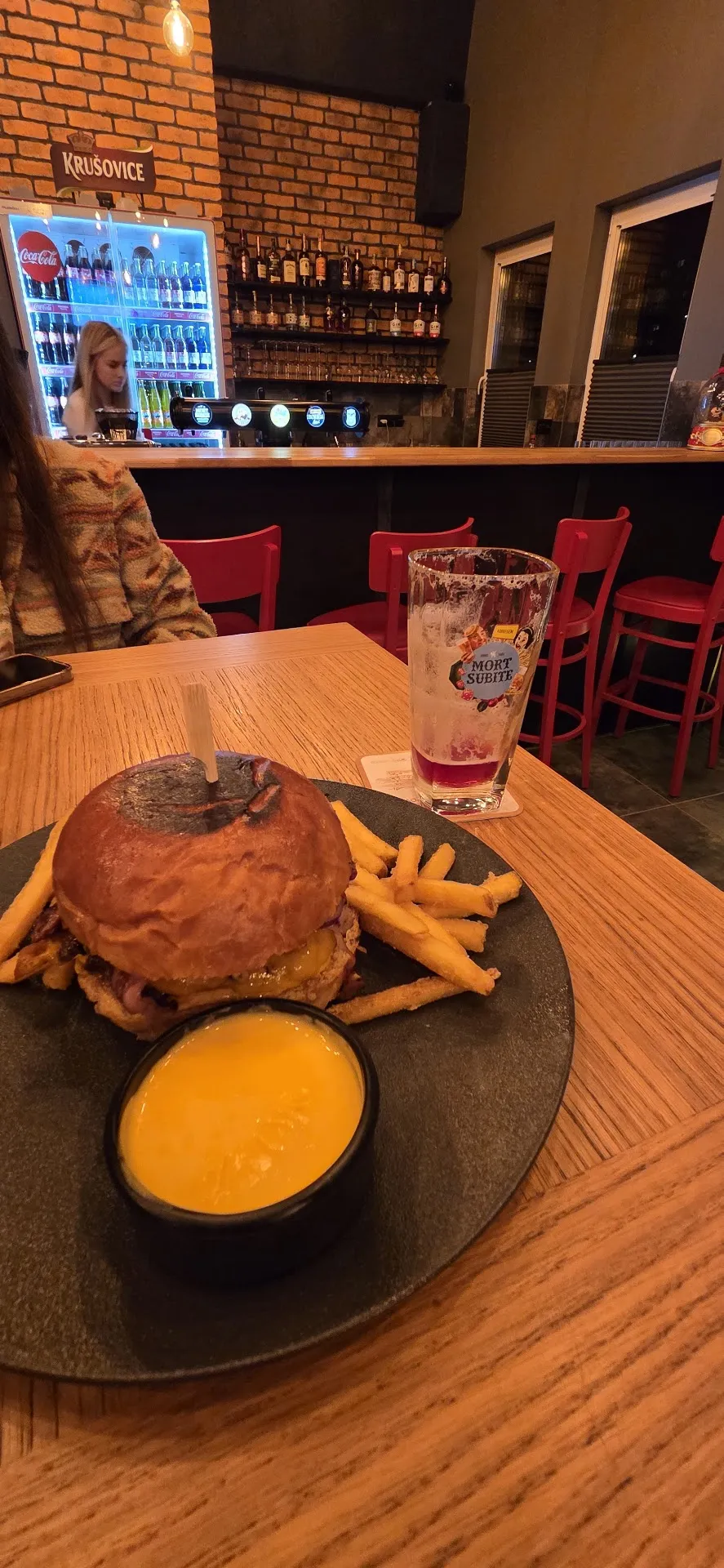 Burger s hranolkami a dipom na stole v pube